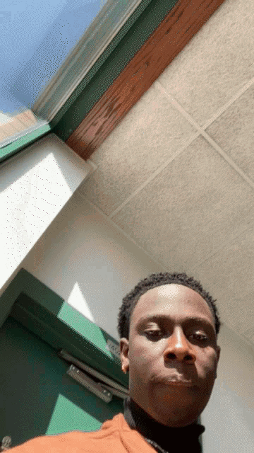 a man taking a selfie in front of a door that says ' nc ' on it