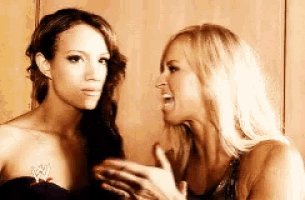 two women are standing next to each other talking to each other .