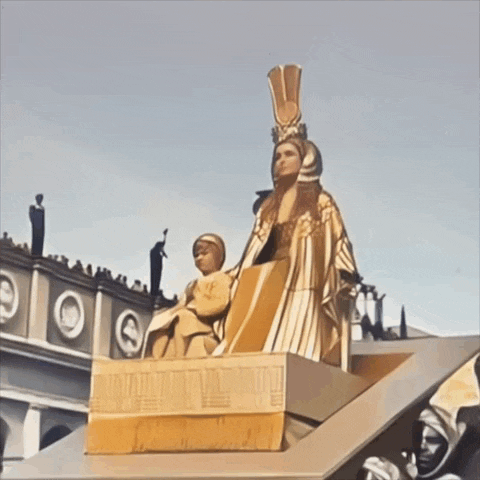 a statue of a woman sitting on a pedestal in front of a building
