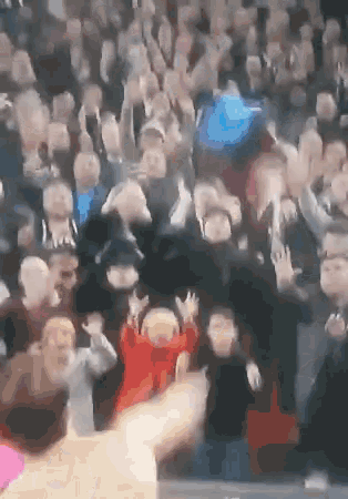 a crowd of people in a stadium with their hands up in the air