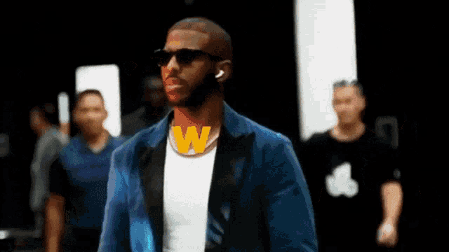 a man wearing sunglasses and a w necklace