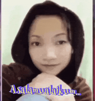 a woman wearing a hooded jacket and a hijab is making a funny face and says assalamualaikum .