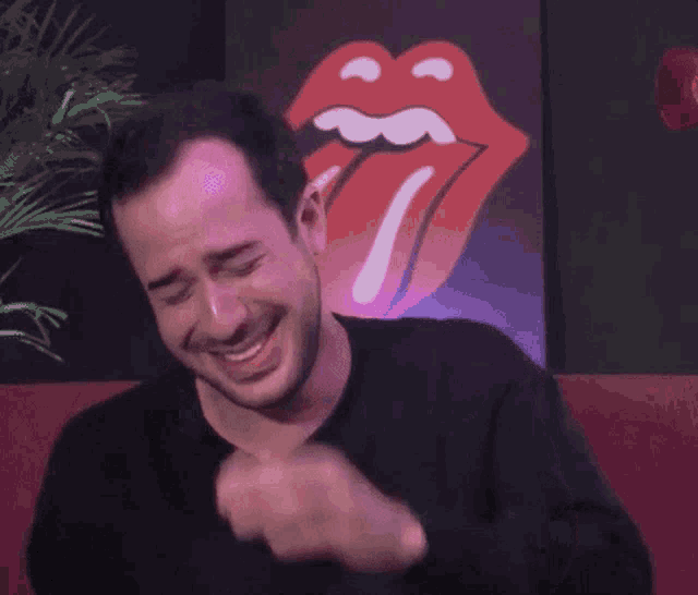 a man making a funny face in front of a rolling stones logo