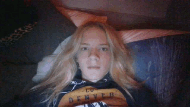 a woman wearing a denver shirt is laying in bed