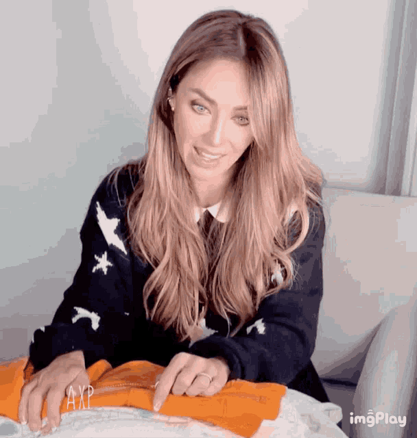 a woman sitting on a couch with a sweater that has the word axp on it