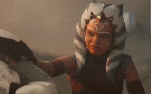 a woman in a star wars costume is holding a gun in her hand and looking at the camera .