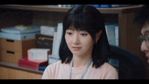 a woman in a pink shirt is sitting in front of a man