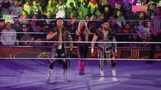 three wrestlers are standing in a ring with a sign that says kosci on it