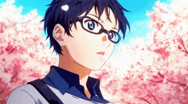 a boy with glasses is standing in front of a tree with cherry blossoms .