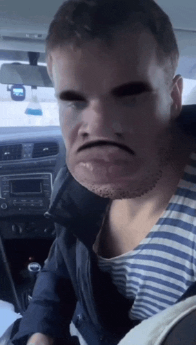 a man in a striped shirt is sitting in a car