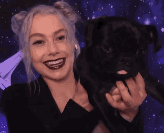 a woman holds a small black dog in her arms and smiles