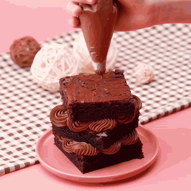 a person frosting a brownie with chocolate frosting