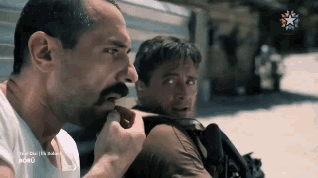 a man with a mustache is biting another man 's ear in a scene from a tv show