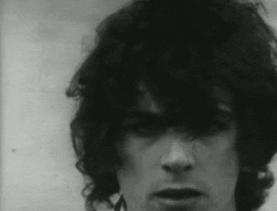 a close up of a man 's face with curly hair in a black and white photo .