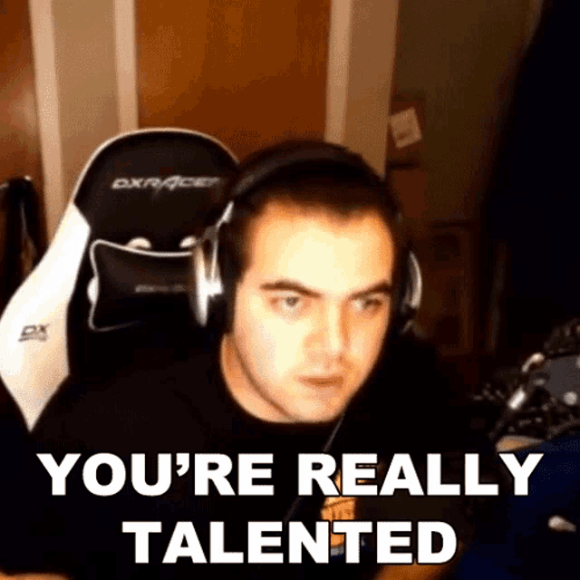 a man wearing headphones says you 're really talented while sitting in a gaming chair .