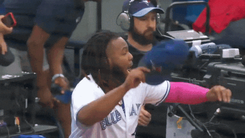 a man wearing a blue jays jersey throws a baseball