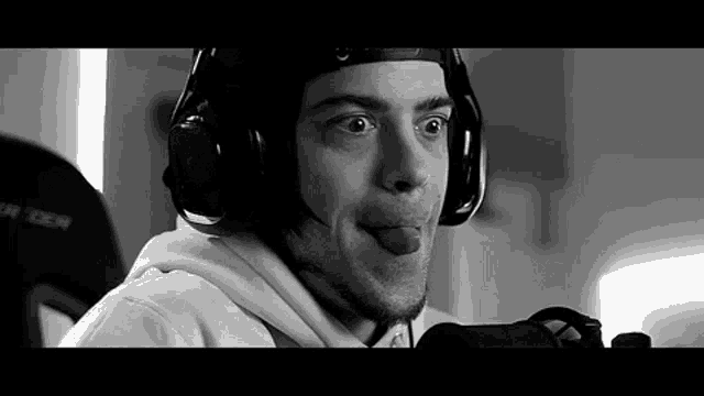 a black and white photo of a man wearing headphones and sticking his tongue out .