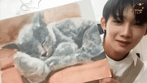 a young man is holding a painting of a cat with the word joker written on the bottom