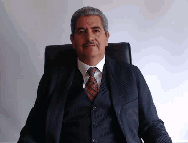 a man wearing a suit and tie is sitting in a chair