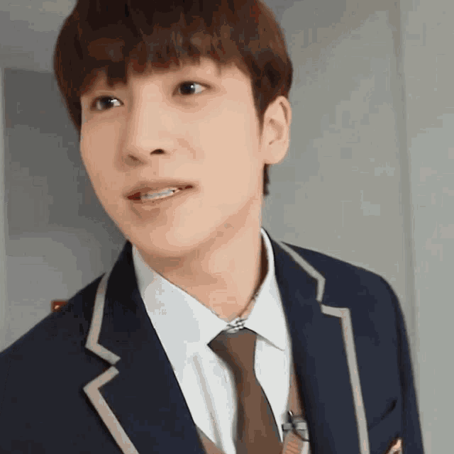 a close up of a young man wearing a school uniform and tie