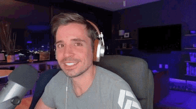 a man wearing headphones is sitting in a chair in front of a microphone .