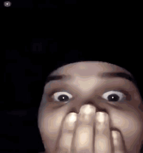 a close up of a person covering their mouth with their hands .