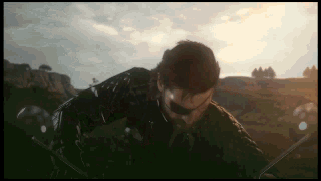 a man in a black jacket stands in a field