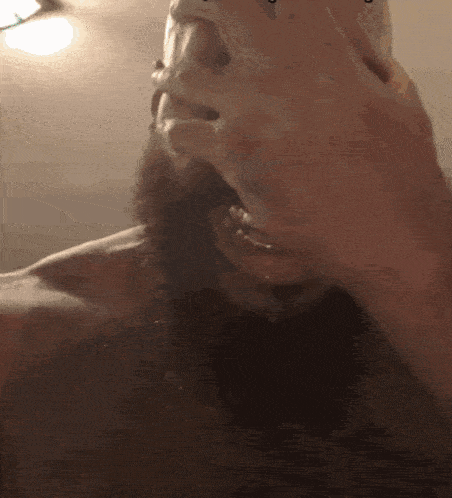 a man with a beard is drinking from a glass with the letter t on it