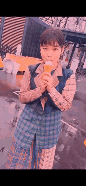 a woman in a plaid dress is holding an ice cream cone
