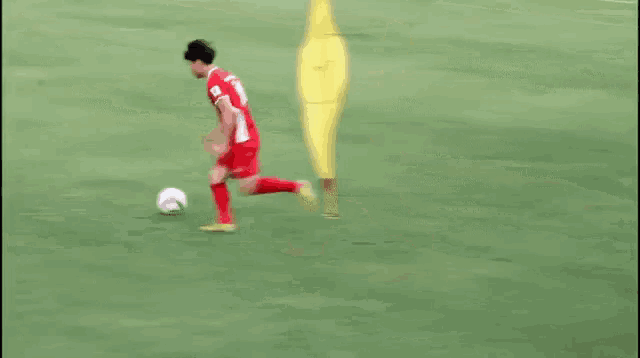 a soccer player in red shorts is kicking a soccer ball on a field .
