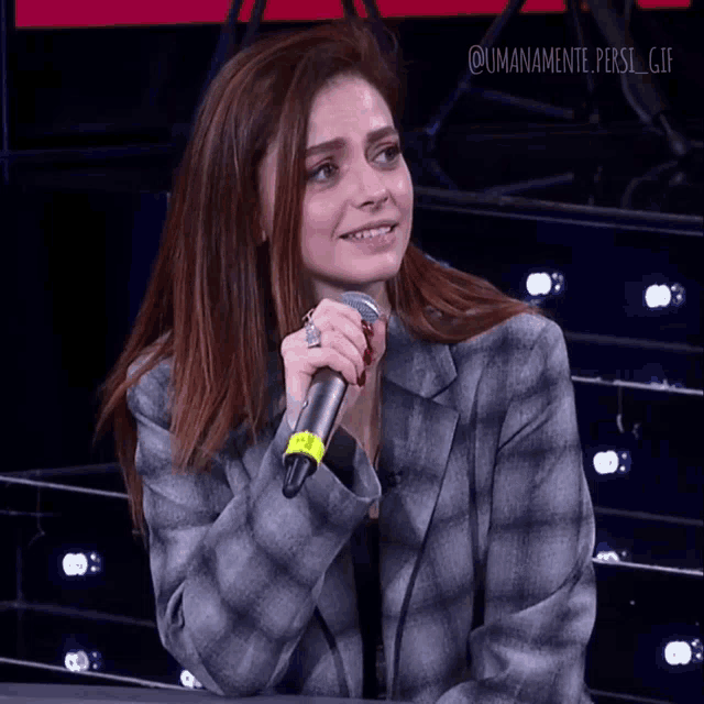 a woman in a plaid jacket is holding a microphone in her hand