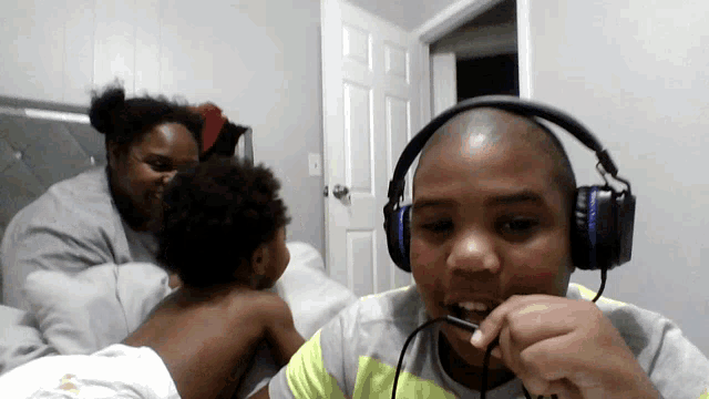 a boy wearing headphones talks into a microphone while a woman looks on