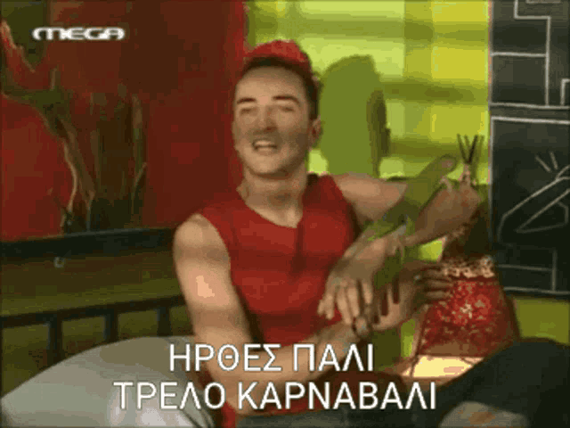 a man in a red tank top is sitting at a table with a mega logo on the bottom right