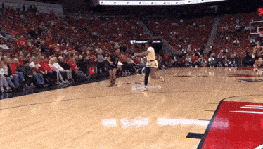 a basketball game is being played in front of a crowd with a sign that says ucla