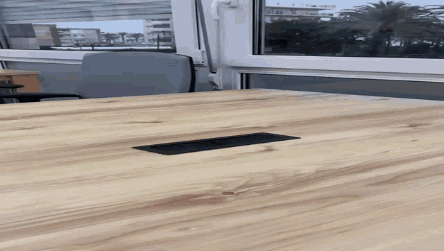 a wooden table in front of a window with palm trees