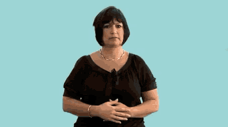a woman in a black shirt is making a funny face while pointing at herself .