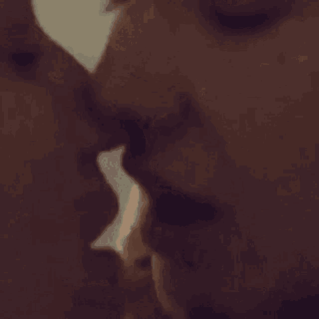 a man and a woman are kissing each other in a close up of their faces .