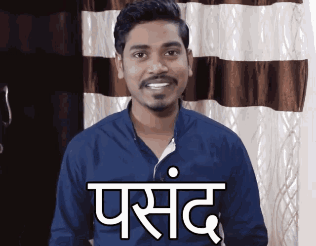 a man in a blue shirt is smiling in front of a brown and white curtain and has the word parsand written on his shirt