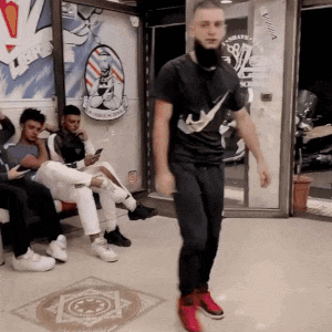 a man in a nike shirt is dancing in a room