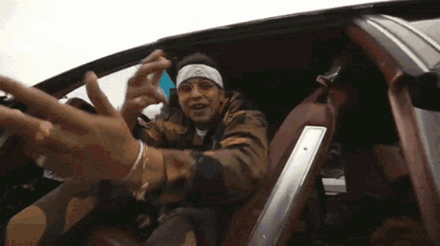 a man wearing sunglasses and a headband is sitting in the driver 's seat of a car