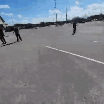 a group of people are walking down a street in a parking lot .