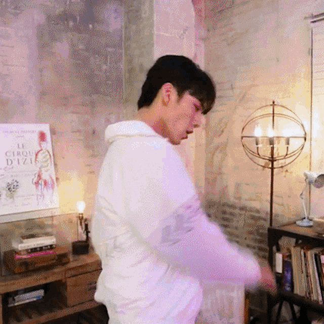 a man is standing in a room with a poster on the wall that says le cirque d' iza