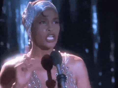 a woman is standing in front of a microphone and singing into it .