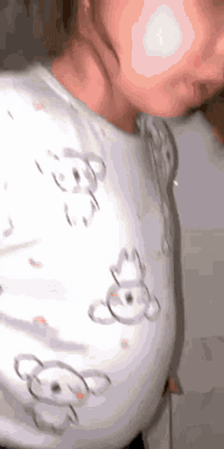 a close up of a baby 's face with a white shirt with teddy bears on it .