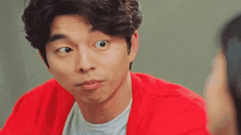 a man in a red sweater is making a funny face while looking at a woman .