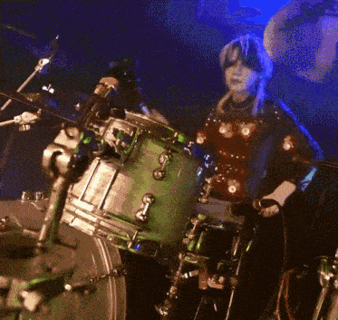 a woman is playing a green drum set