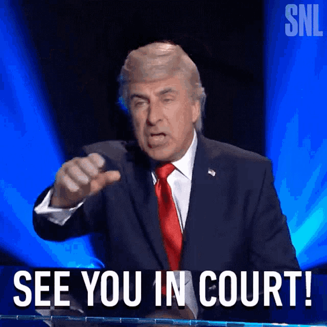 a man in a suit and tie is giving a speech and says see you in court
