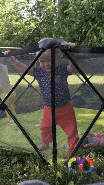 a baby is standing in a fenced in area