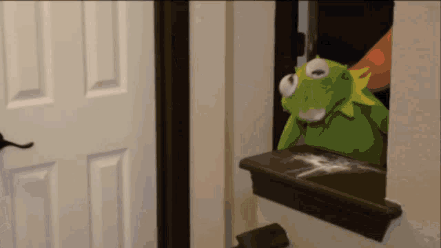 kermit the frog is looking out of a window with a few drops of milk on it