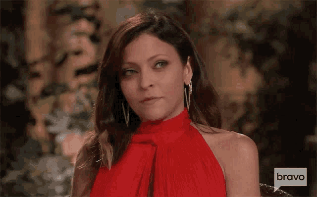 a woman wearing a red dress and earrings is sitting in a chair .